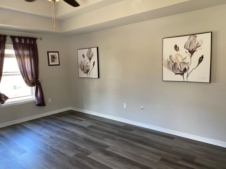 A living room with two paintings on the wall and a ceiling fan.