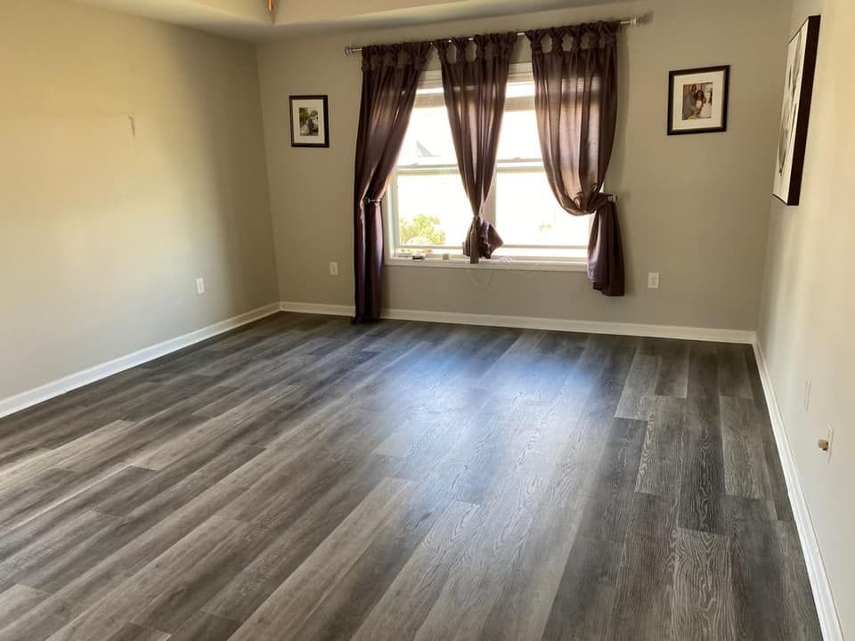 An empty living room with hardwood floors and a window.