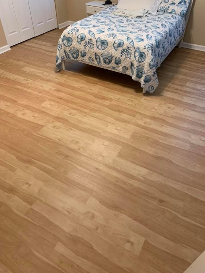 A bedroom with hardwood floors and a bed with a blue and white comforter.