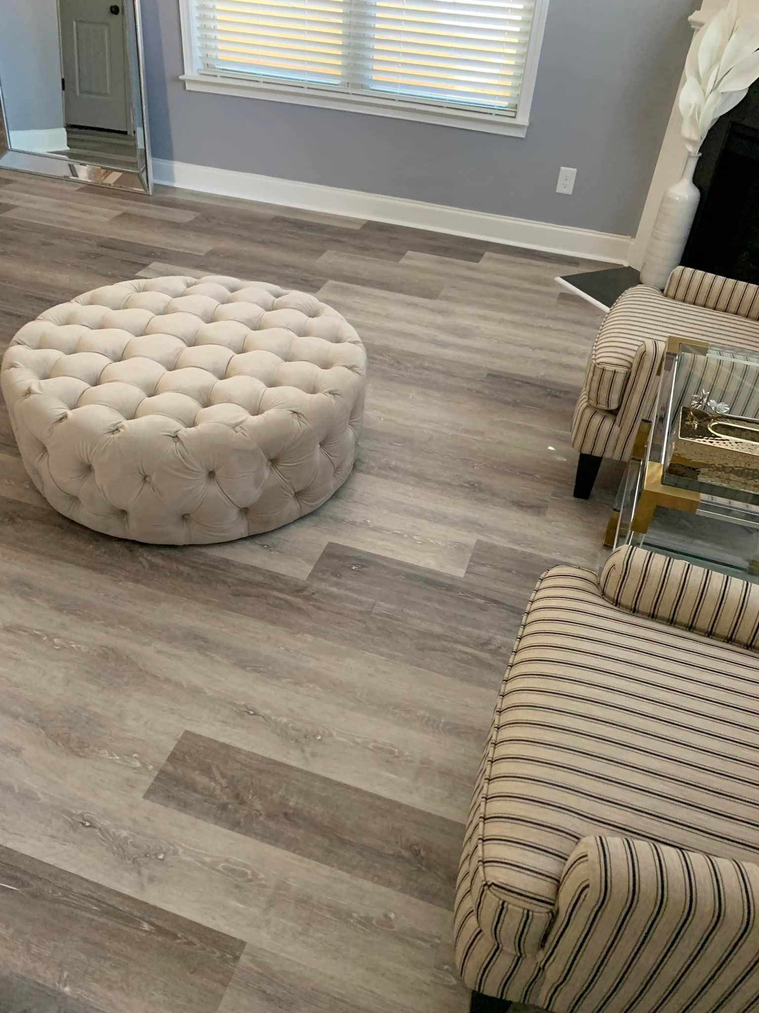 A living room with a round ottoman , chairs , and a coffee table.