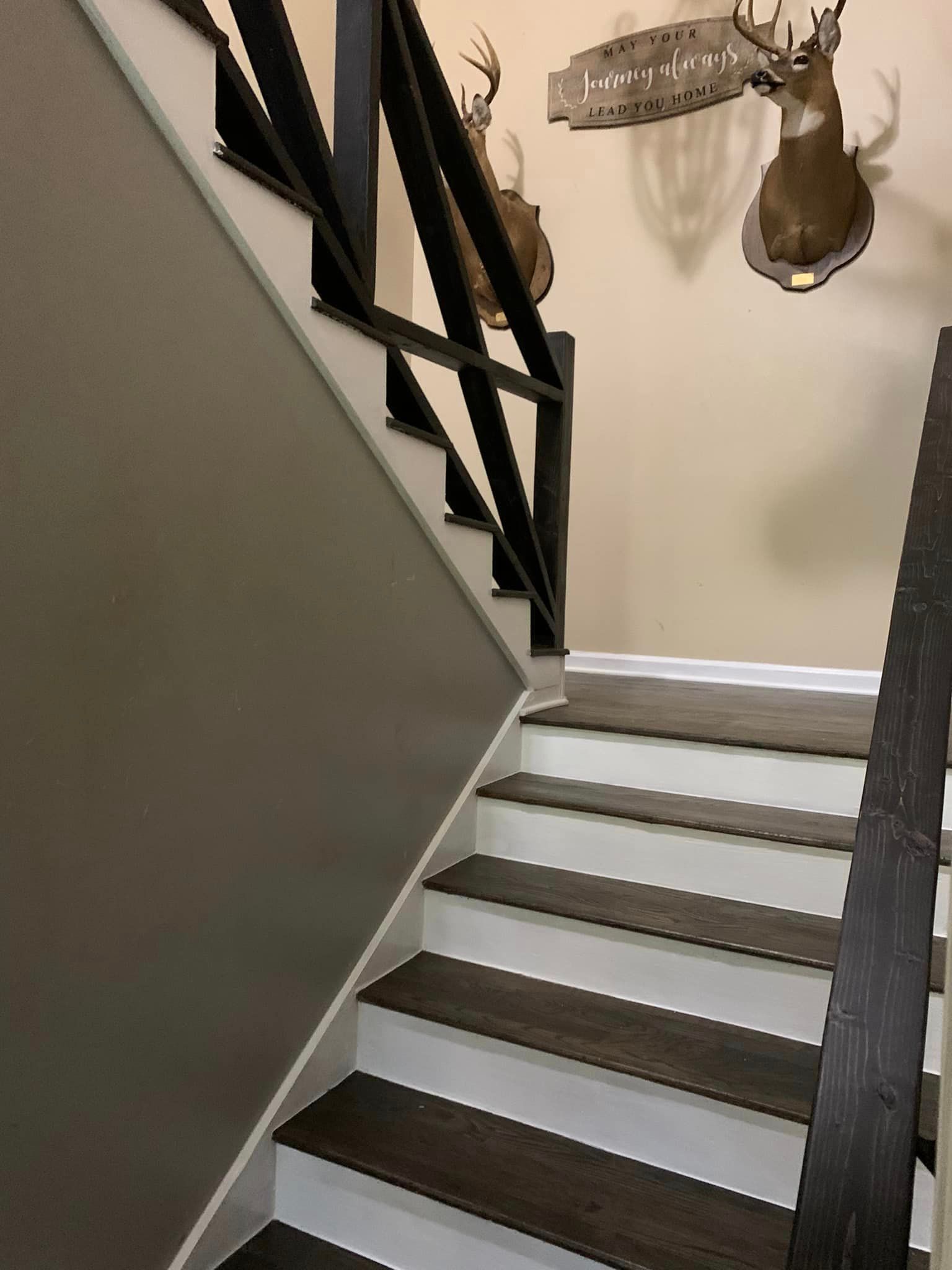 A staircase with two deer heads hanging on the wall.