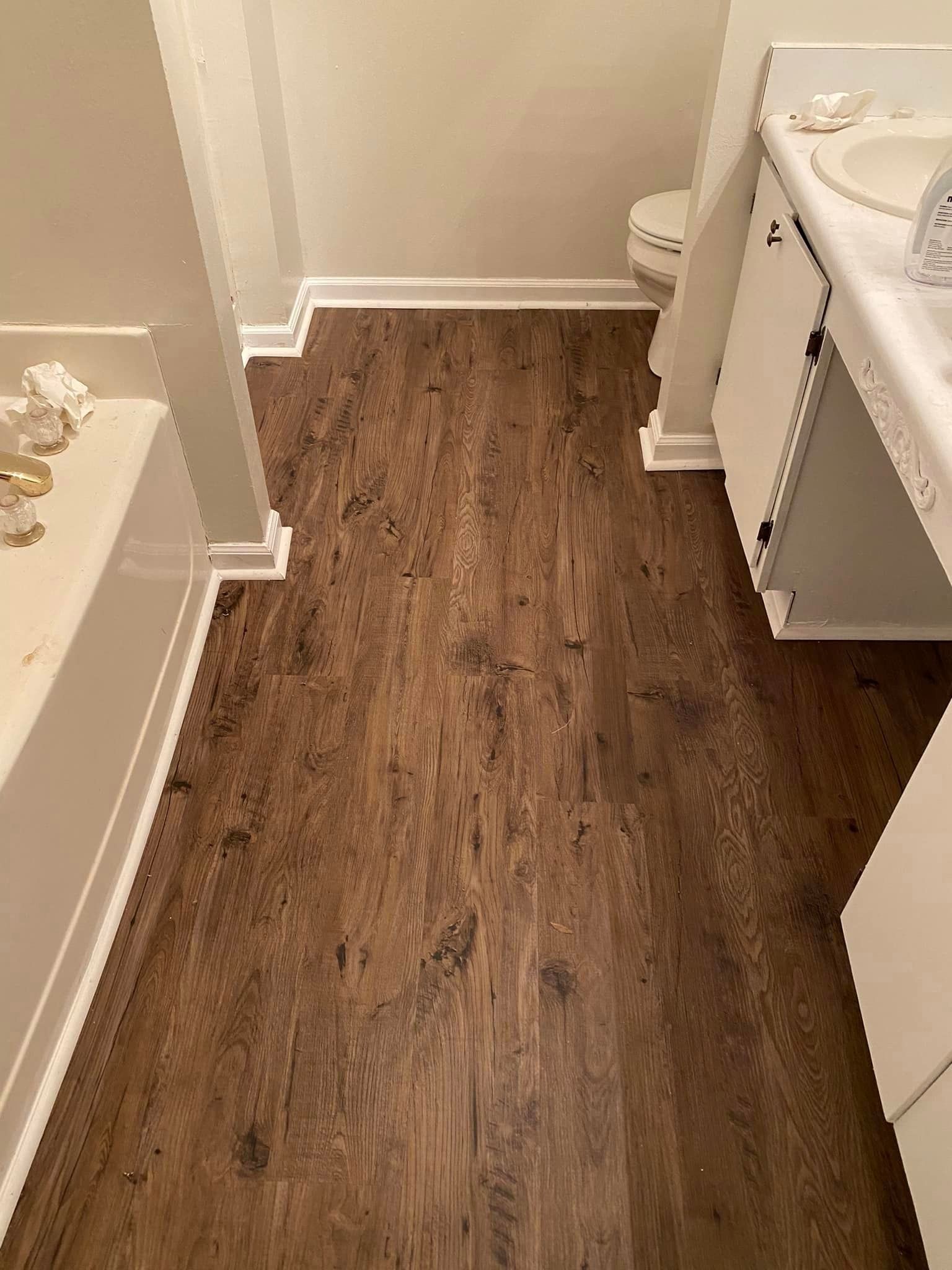 A bathroom with a wooden floor , sink , toilet and bathtub.