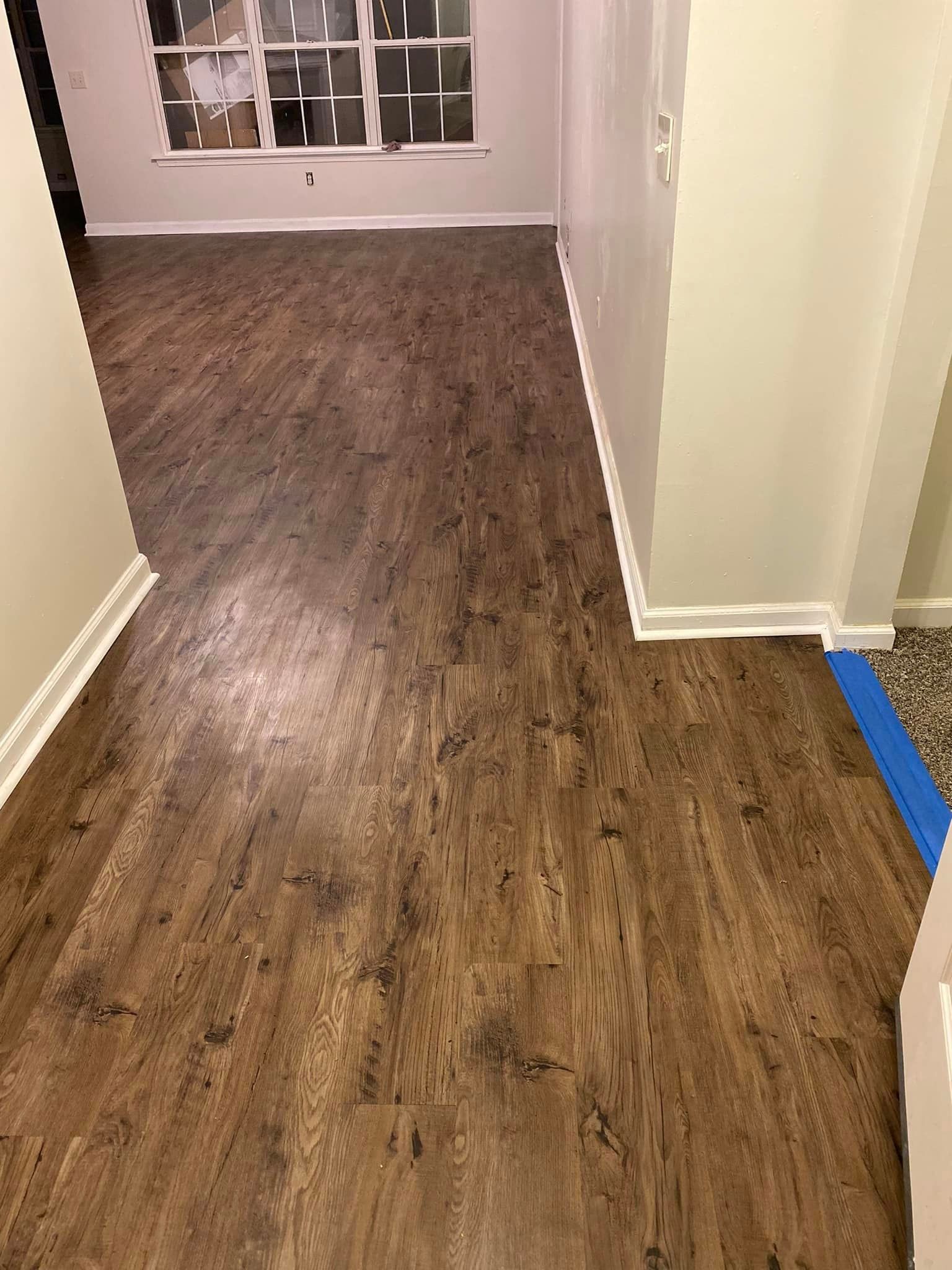 A hallway with hardwood floors and a window in a house.