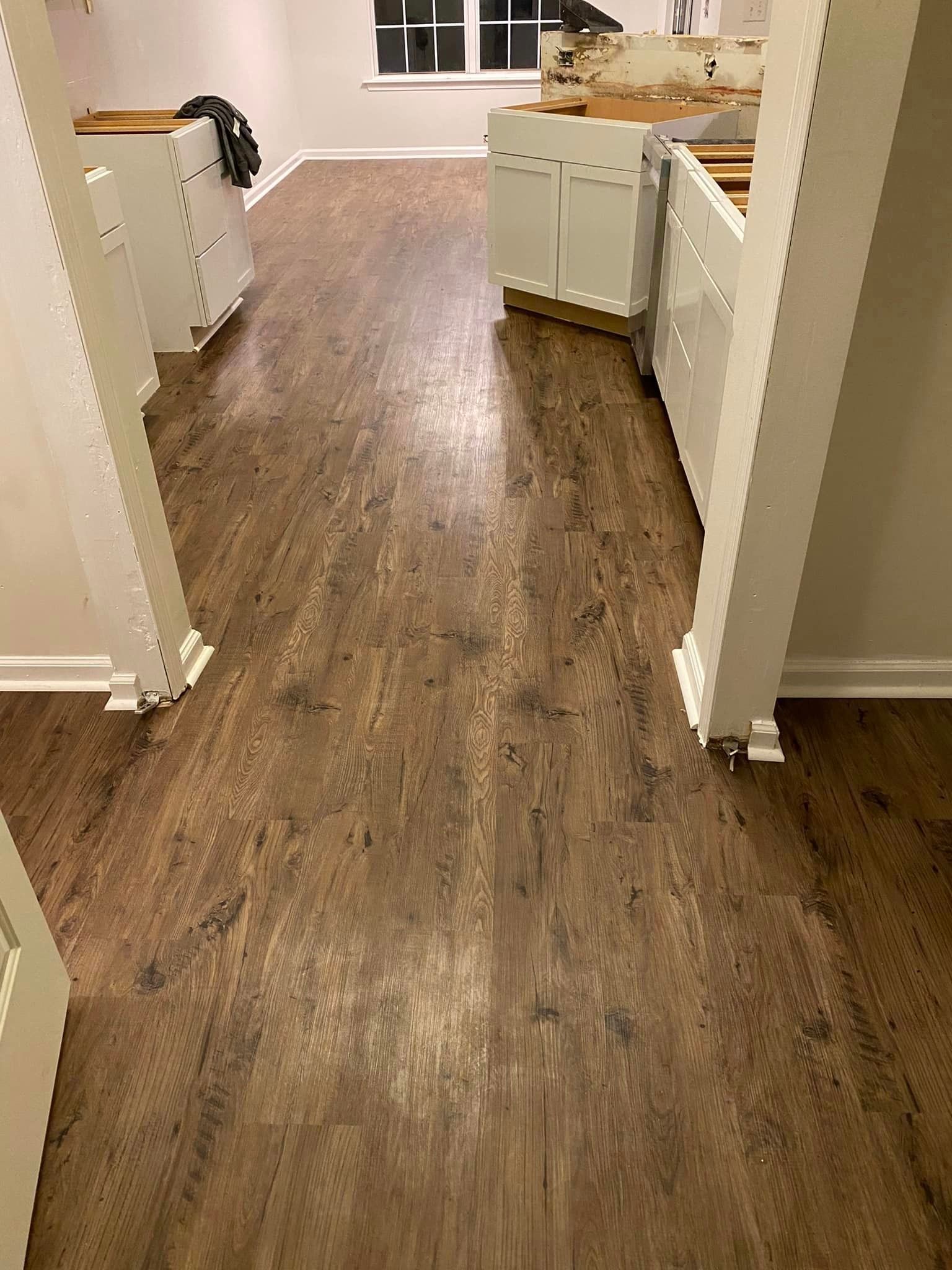 A kitchen with a wooden floor and white cabinets.
