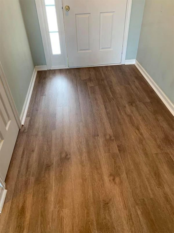 A hallway with a wooden floor and a white door.