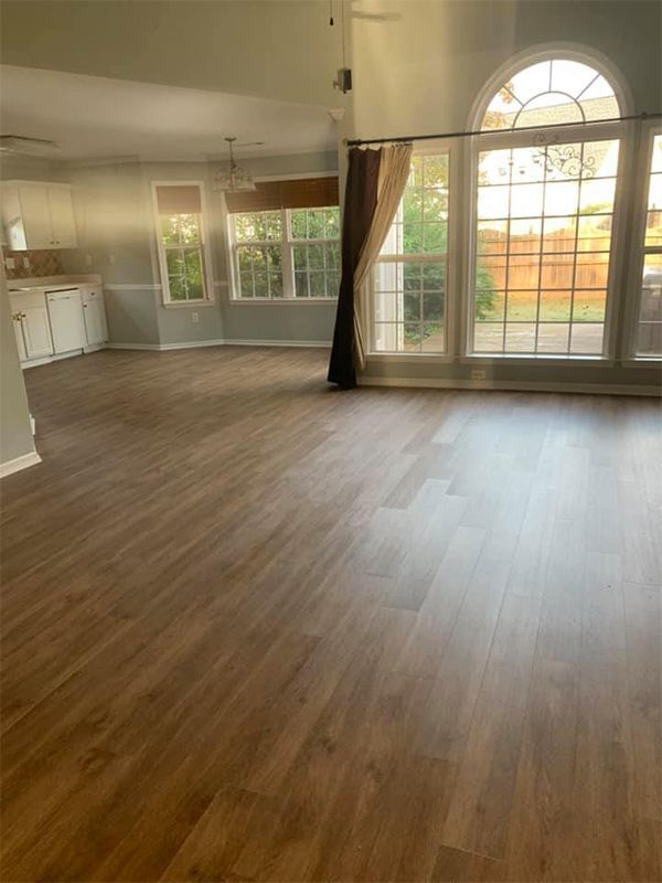 An empty living room with hardwood floors and sliding glass doors.