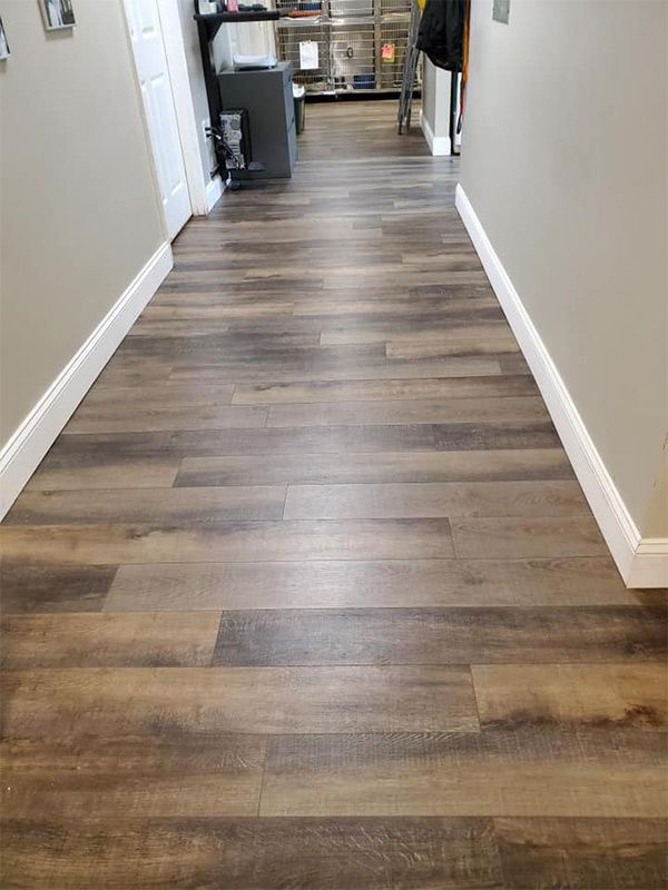 A hallway with a wooden floor and white trim.