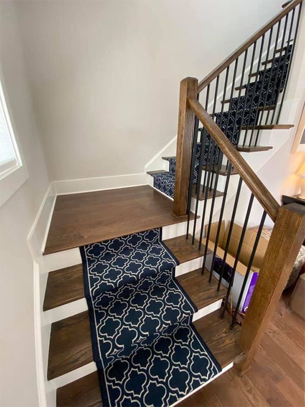 A staircase with a blue carpet on the steps and a wooden railing.