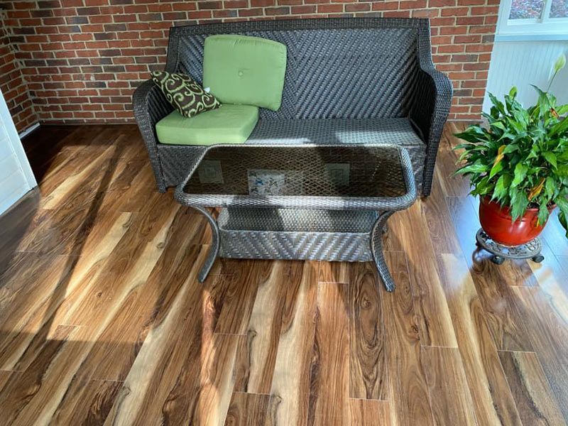 A wicker couch and coffee table are sitting on a wooden floor next to a potted plant.