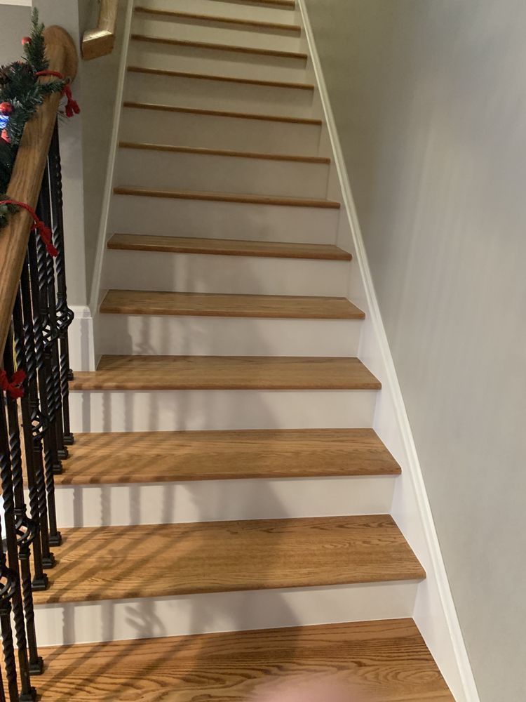 A wooden staircase with white steps and a black railing