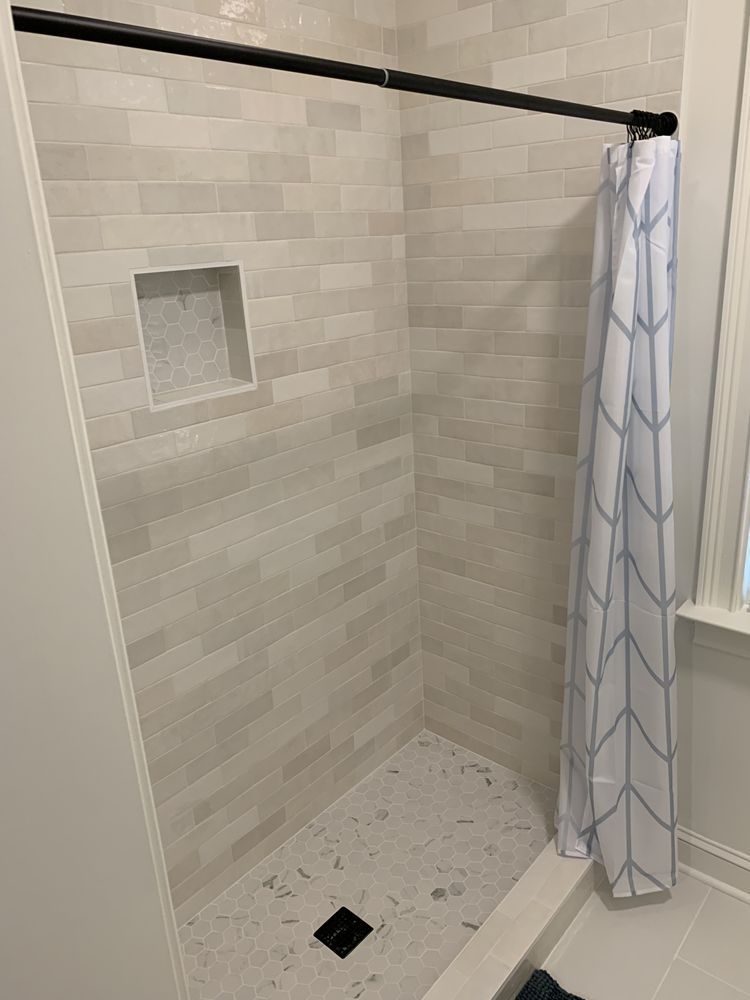 A shower stall with a shower curtain and a window in a bathroom.