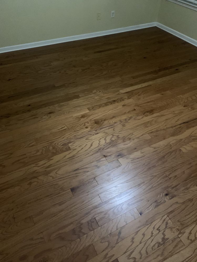 A bedroom with hardwood floors and a window.