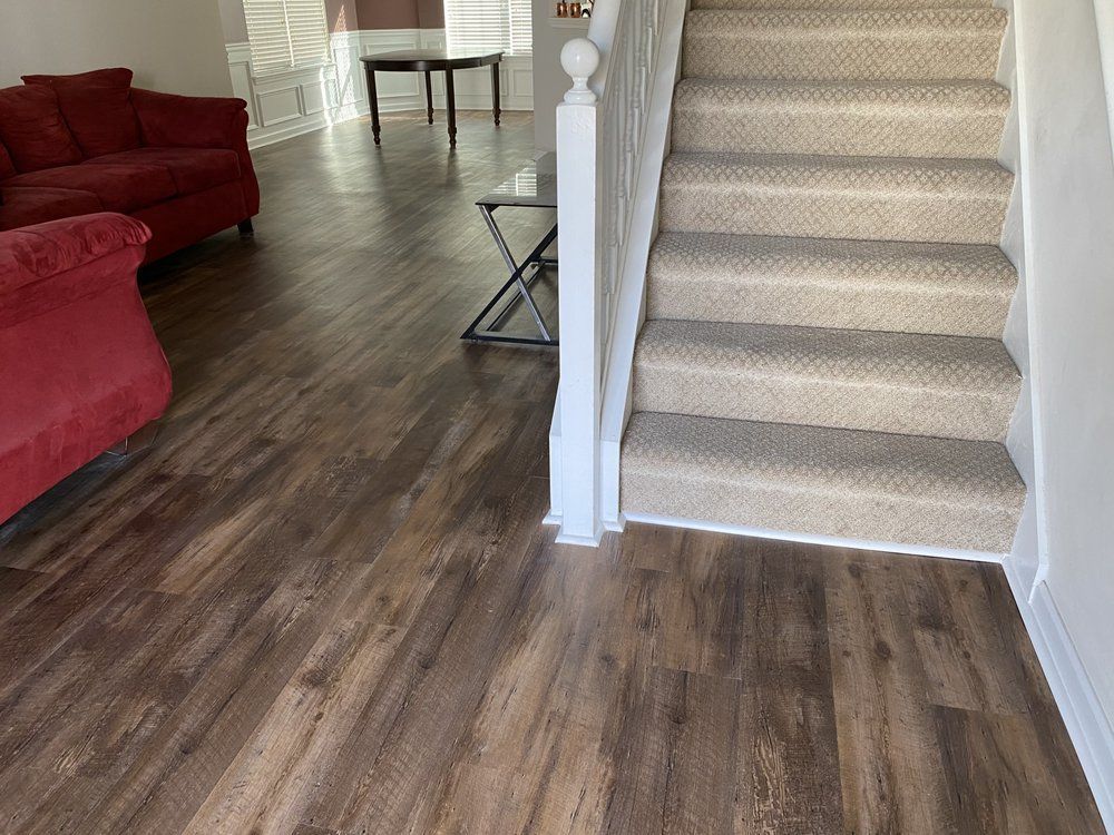 A living room with hardwood floors and stairs leading up to the second floor.
