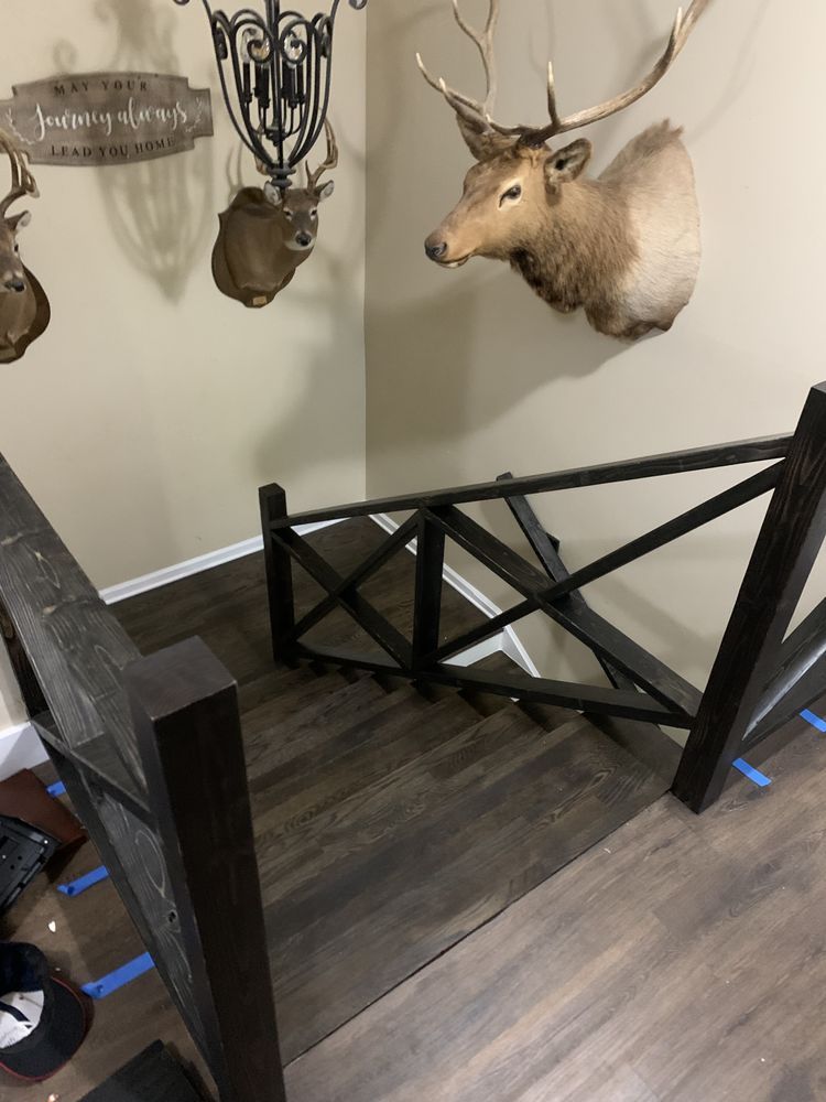 A deer head is hanging on the wall above a wooden staircase.