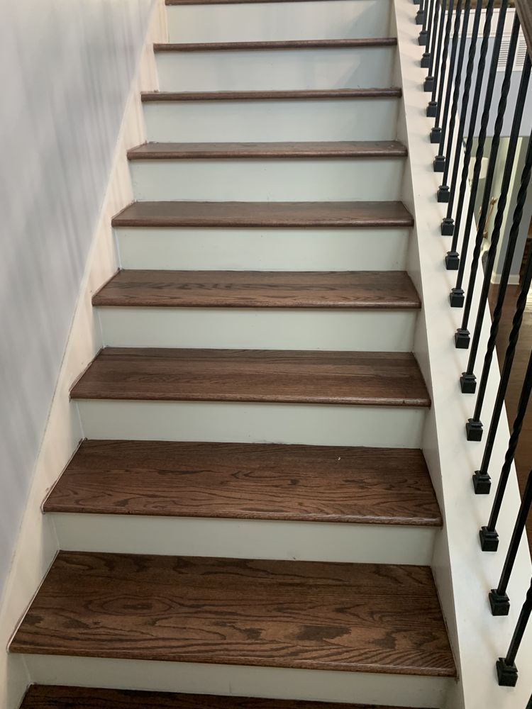 A set of wooden stairs with white steps and a black railing.
