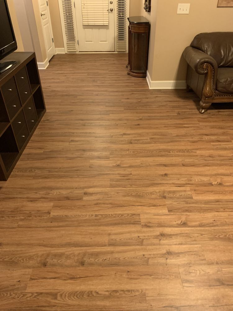 A living room with hardwood floors , a couch , and a television.