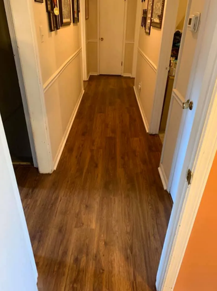 A hallway with hardwood floors and white walls in a house.