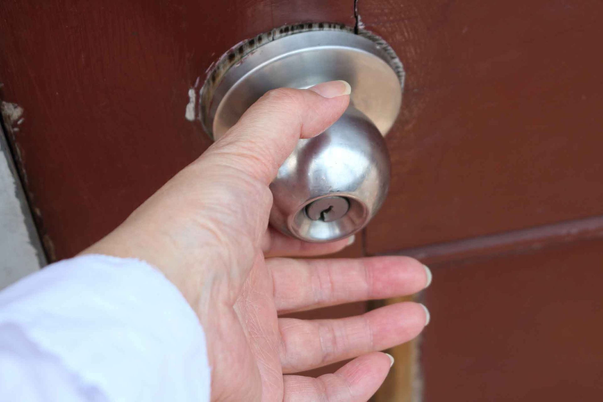 A person is holding a door knob in their hand.
