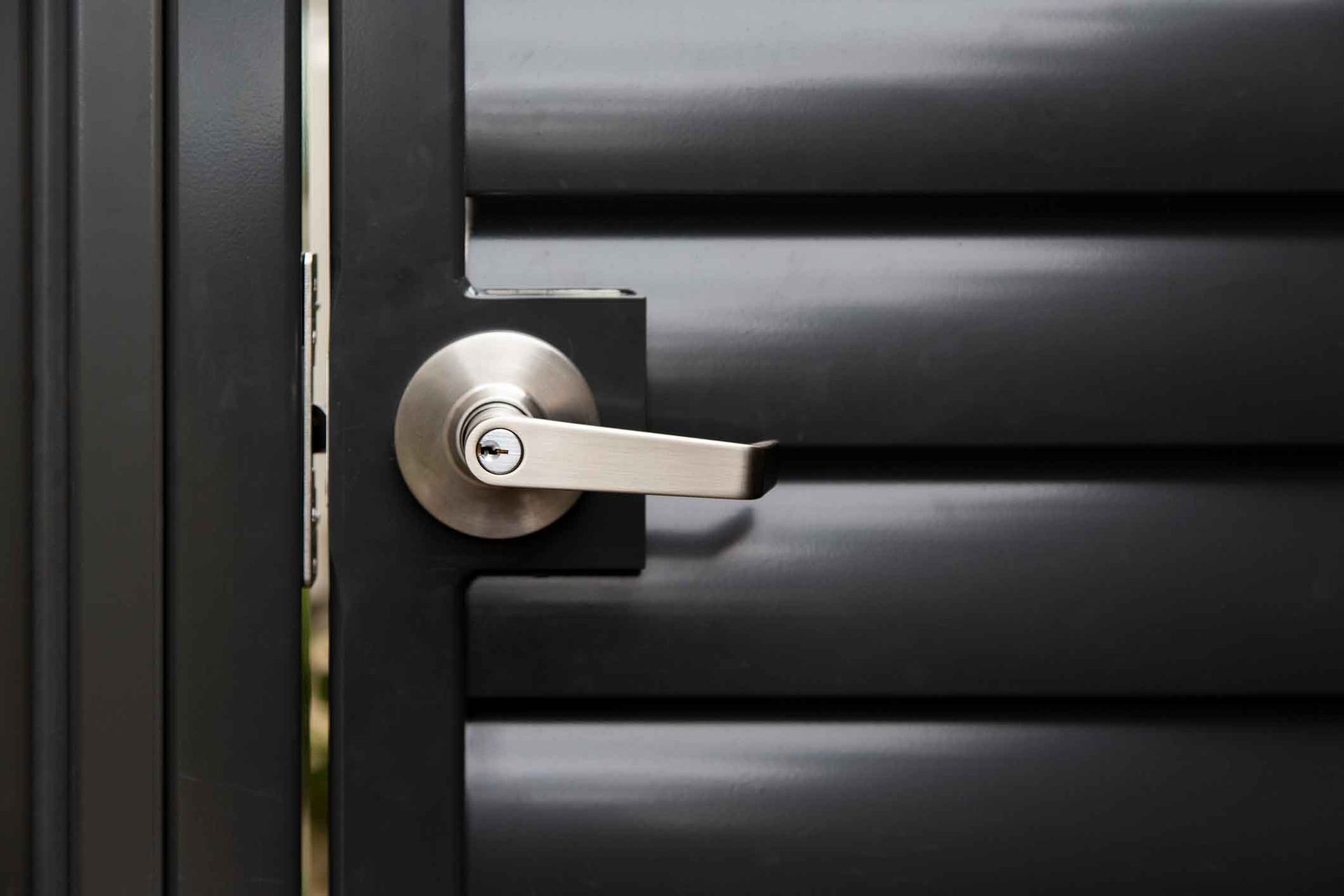 A close up of a door handle on a black door.