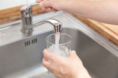Filling up a glass with drinking water from kitchen tap — plumbing pipe maintenance Goleta, CA