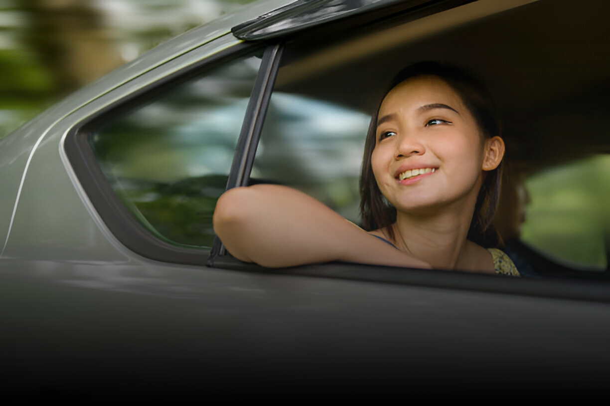 一名婦女坐在車裡，看著窗外。