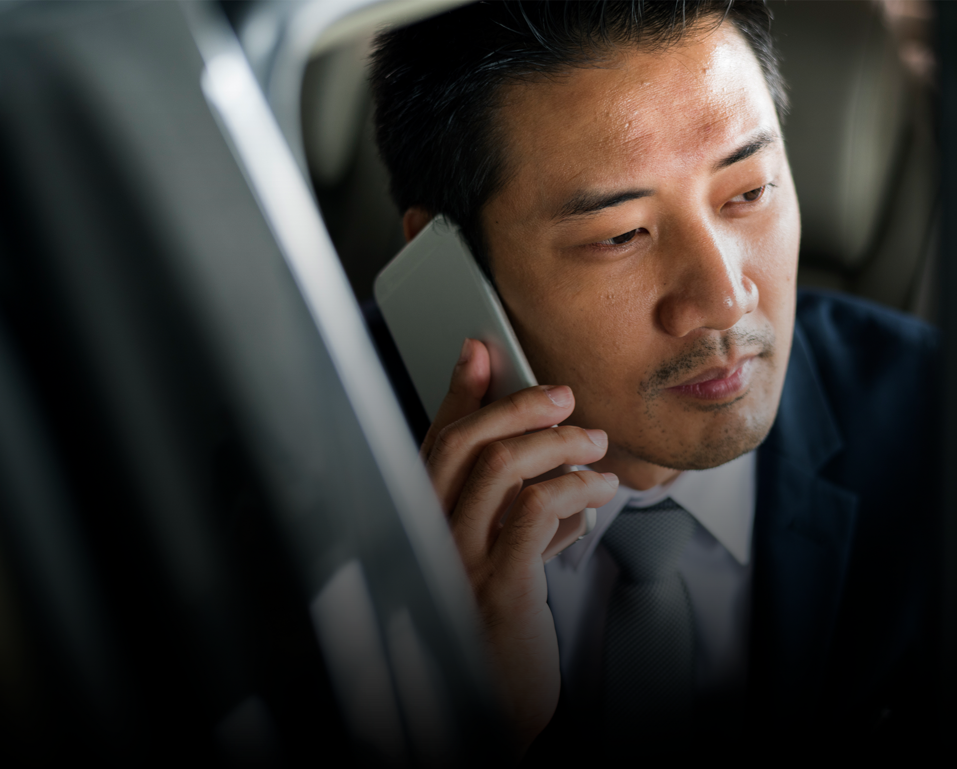 一名西裝革履的男子正在車上用手機通話。