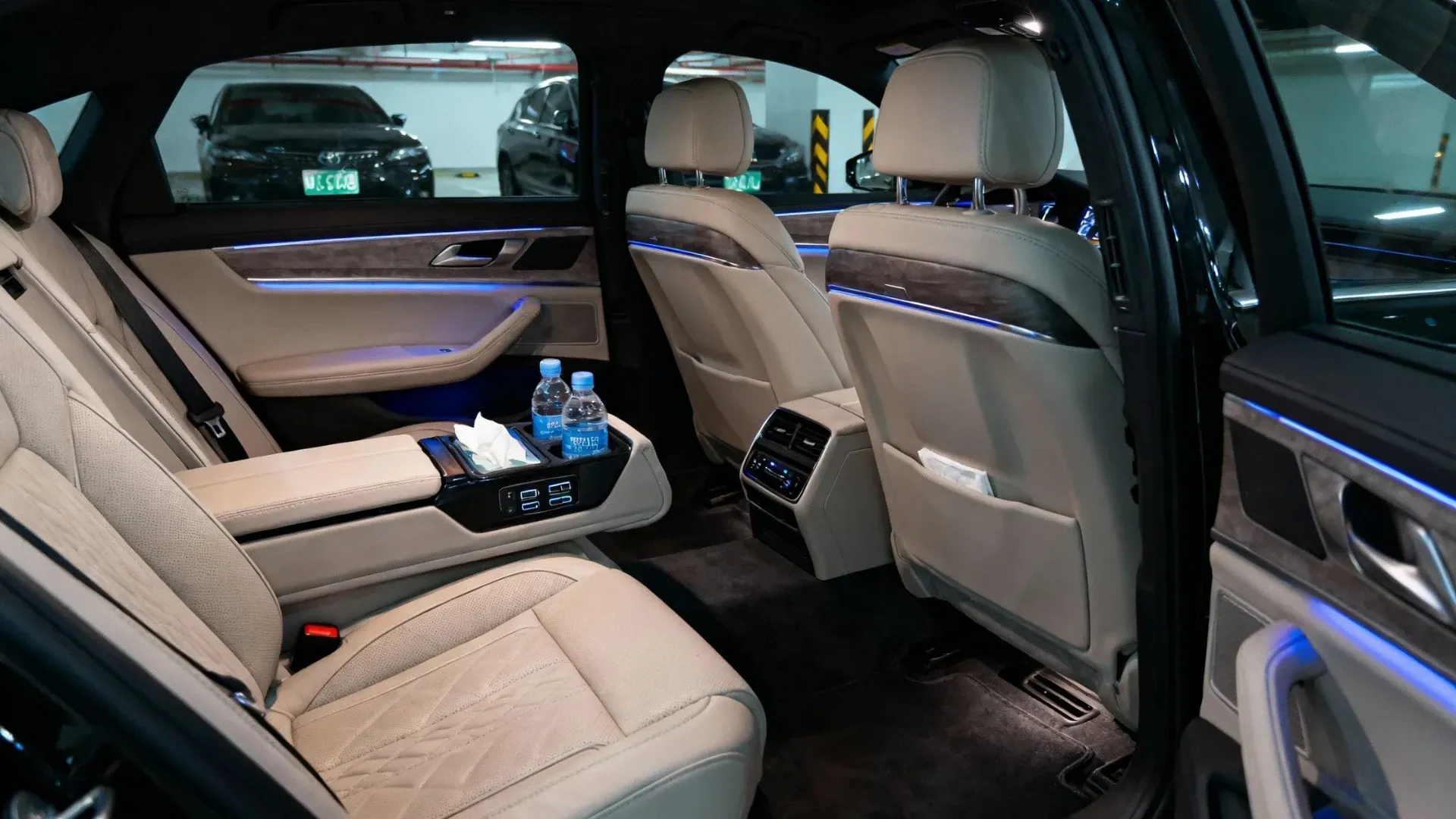 商務轎車寬敞內裝與後廂行李空間示意,後座腿部空間充裕,USB充電與瓶裝水等細節,符合商務包車需求。