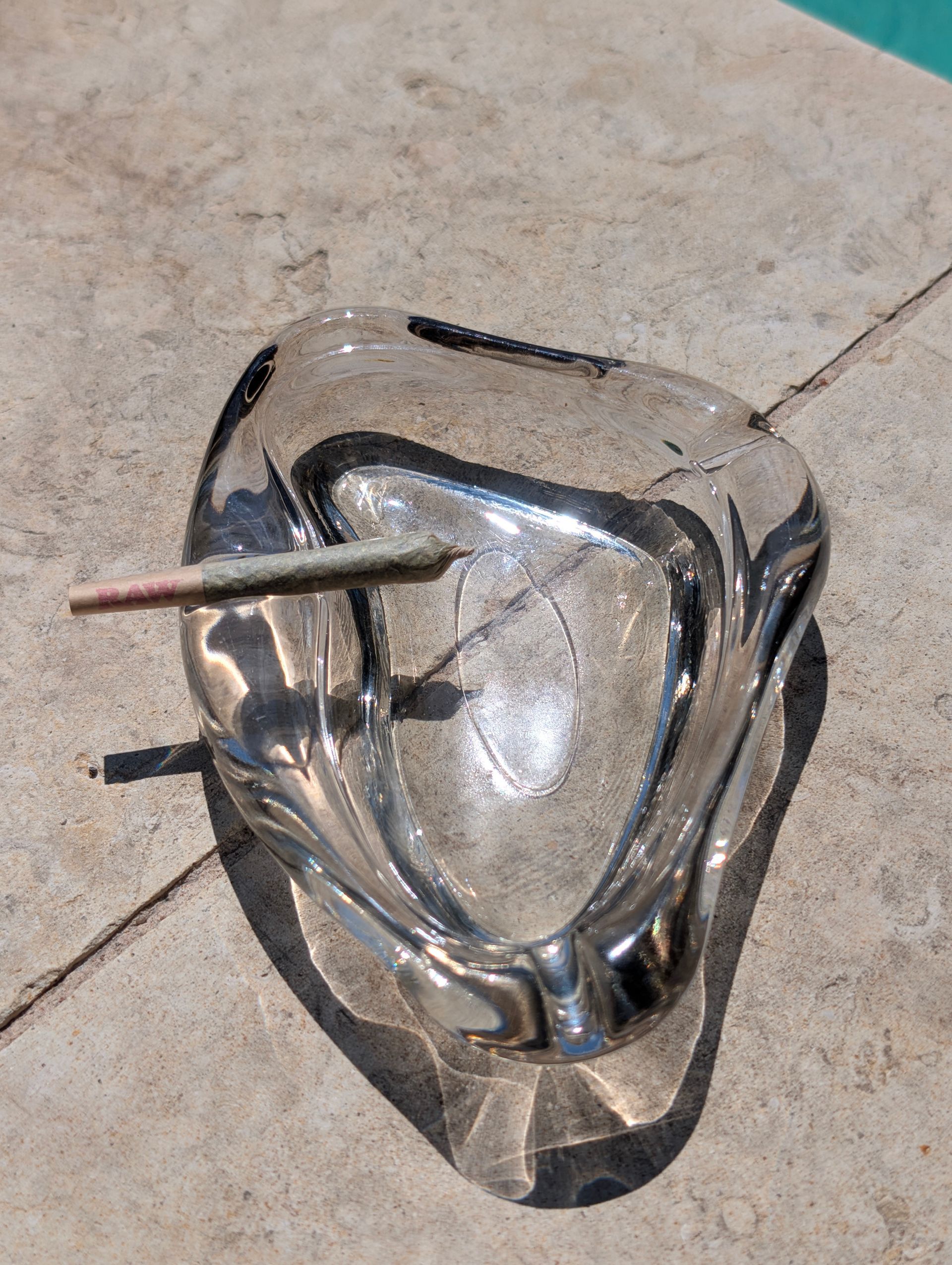 Broken clear glass object on a tiled floor with metal rods sticking through it