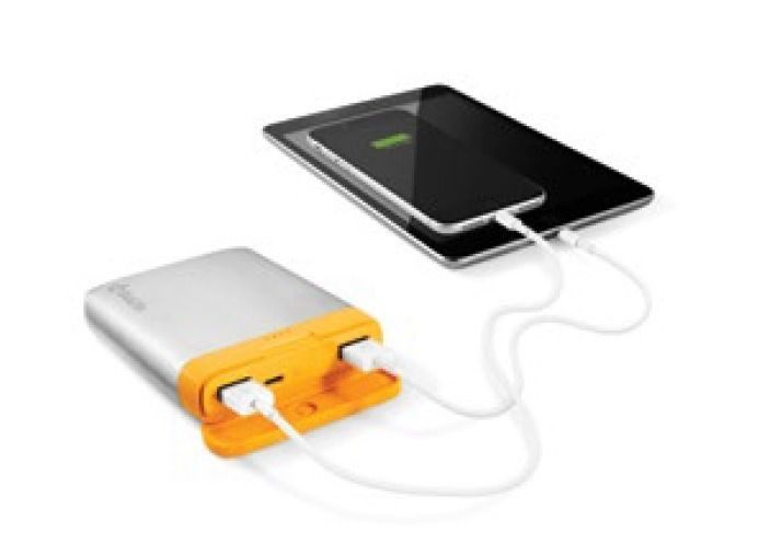Portable power bank charging a tablet and a phone with white cables.
