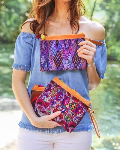 Woman holding two colorful patterned clutch bags.