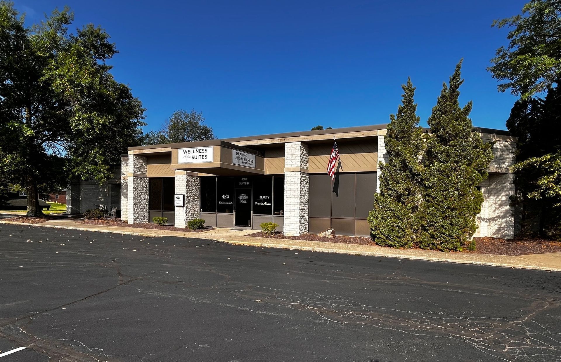 Single-story commercial building that reads Wellness Suites on the front under a clear blue sky.