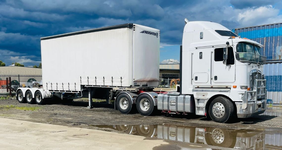 A Truck With a Trailer in a Muddy Field — Goulburn Transport In Goulburn, NSW