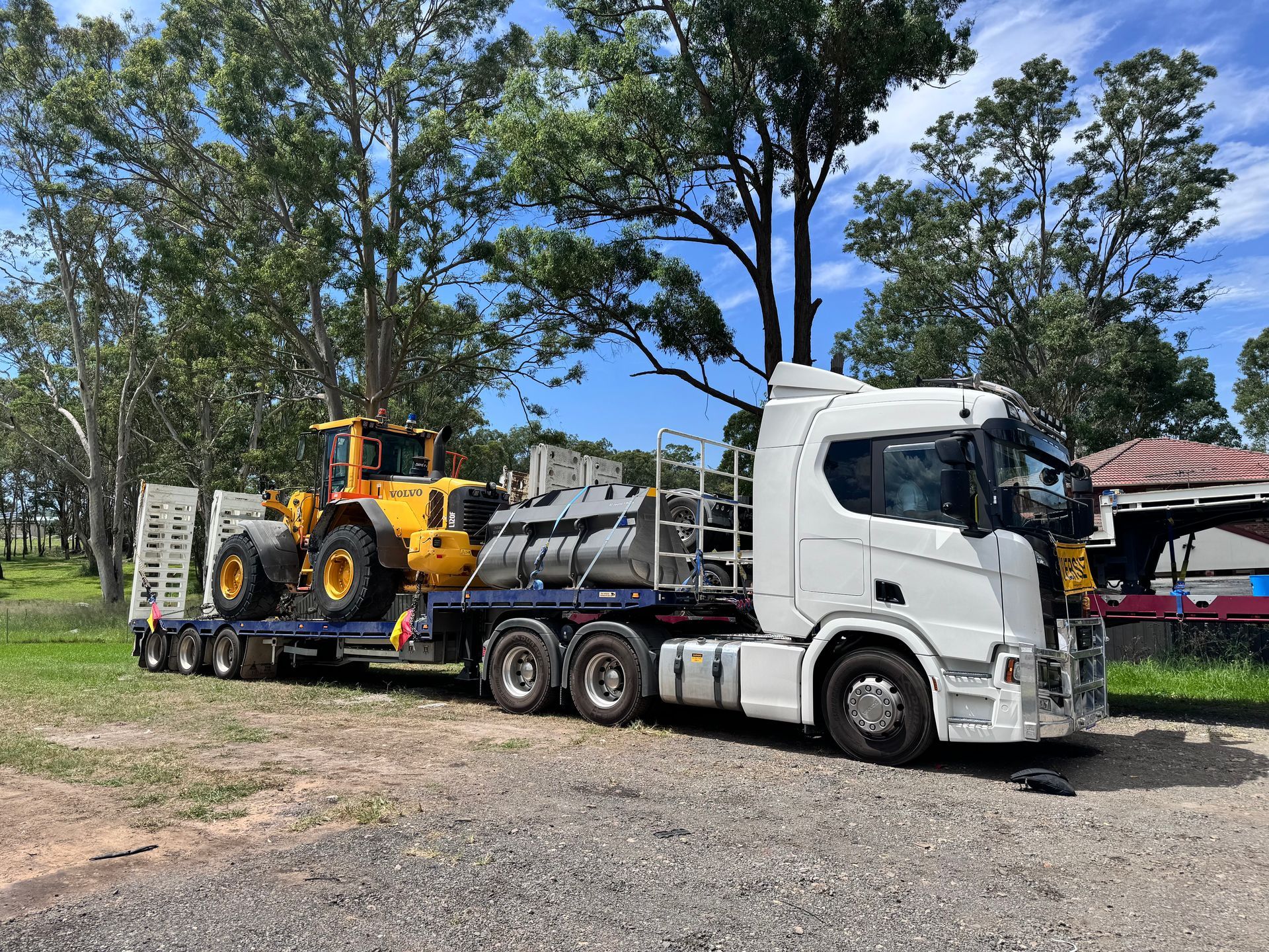 A yellow tractor being hauled by a truck — Goulburn Transport In Goulburn, NSW