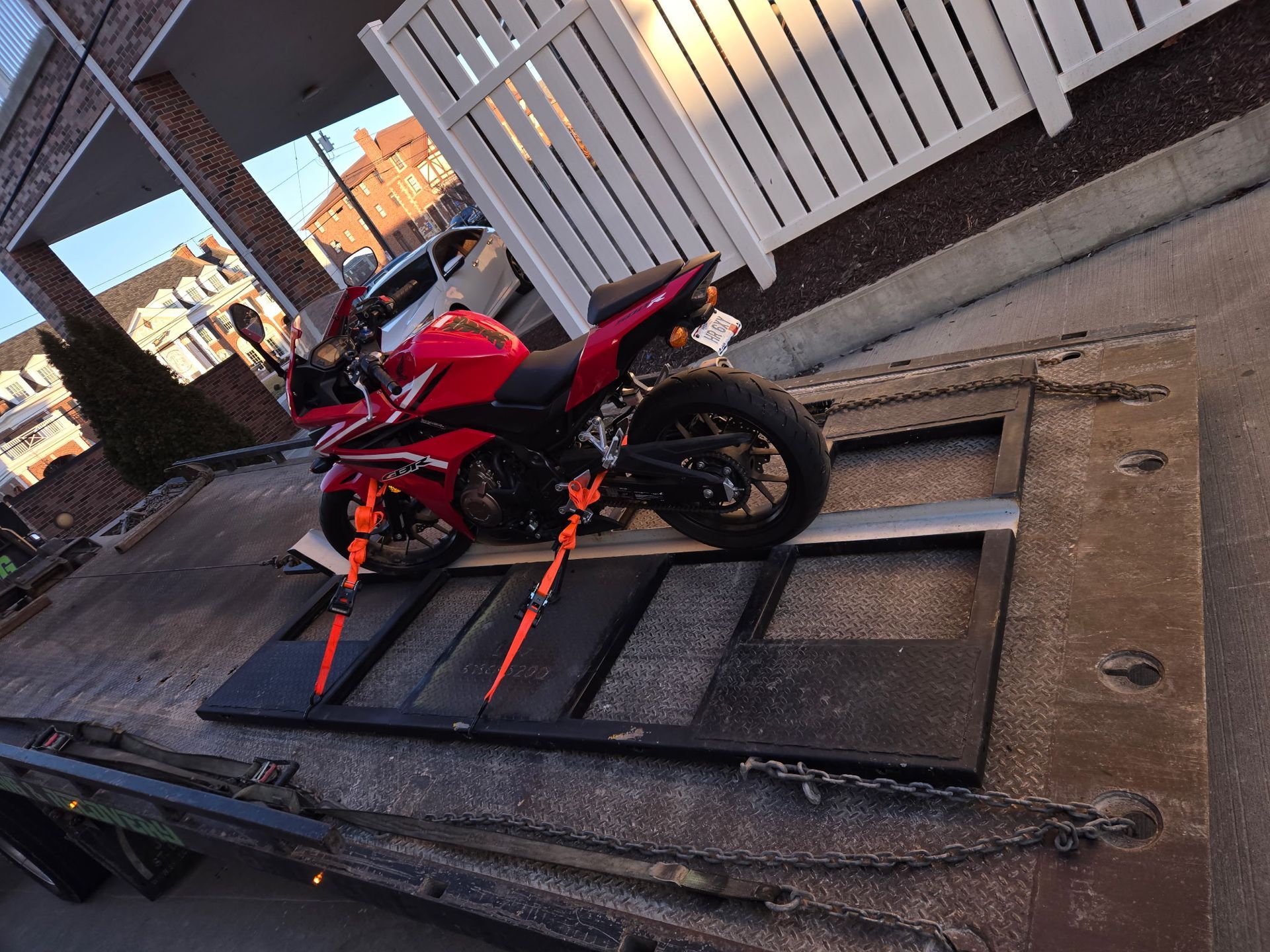 Red motorcycle secured on a flatbed tow truck, ready for transport.
