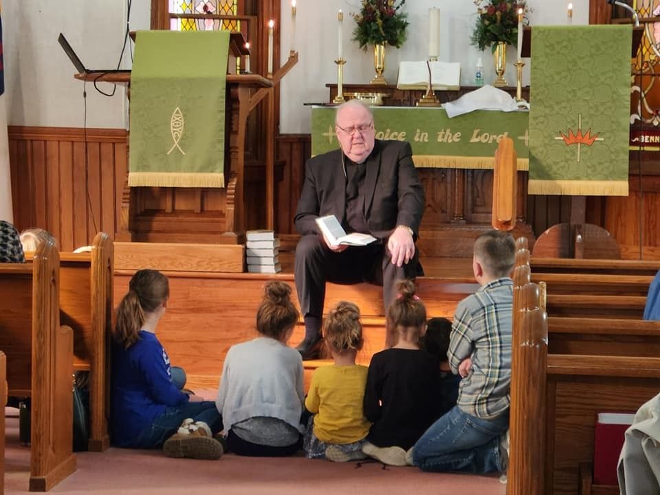 A man is reading a book to a group of children in a church
