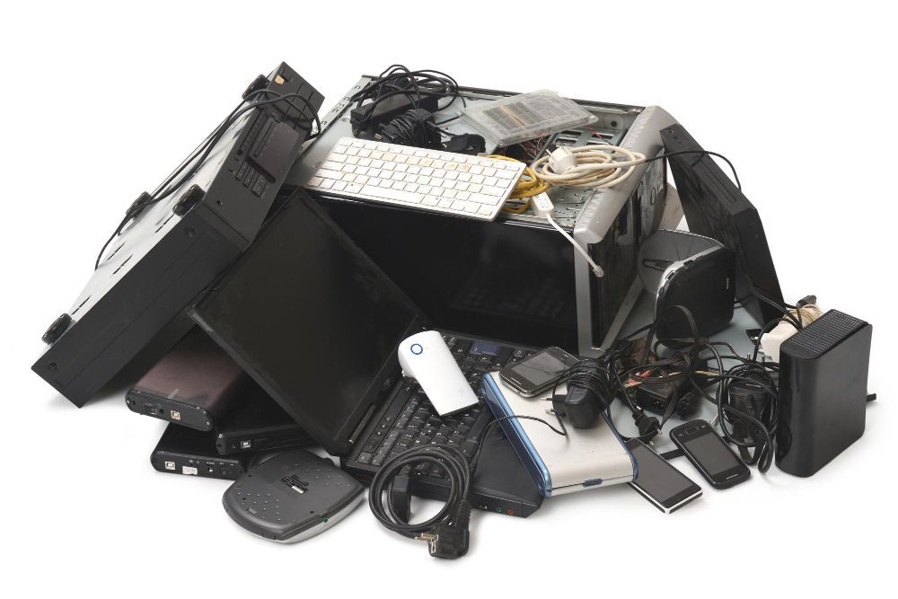 A pile of old electronic devices including a keyboard
