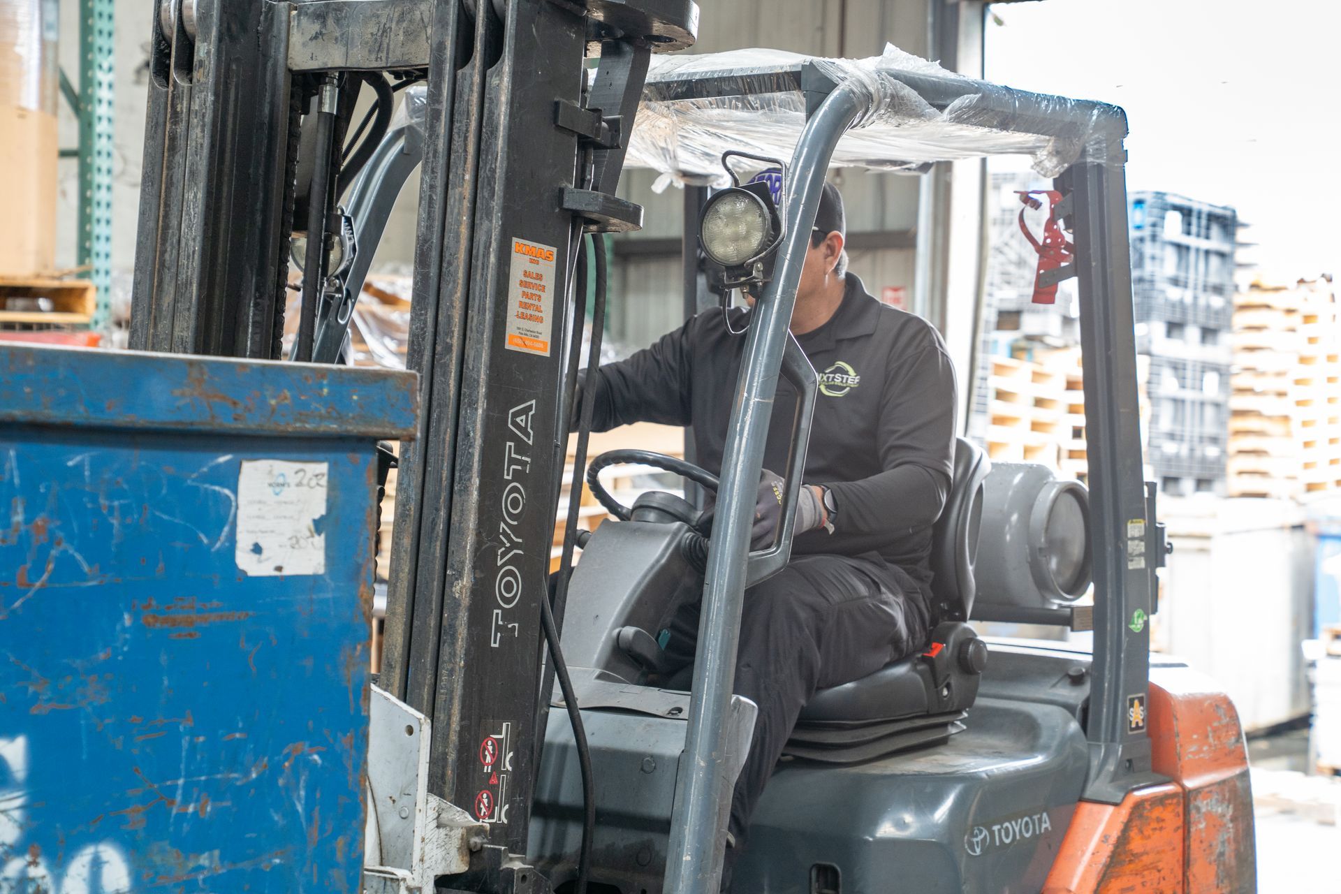 A man is driving a forklift in a warehouse.