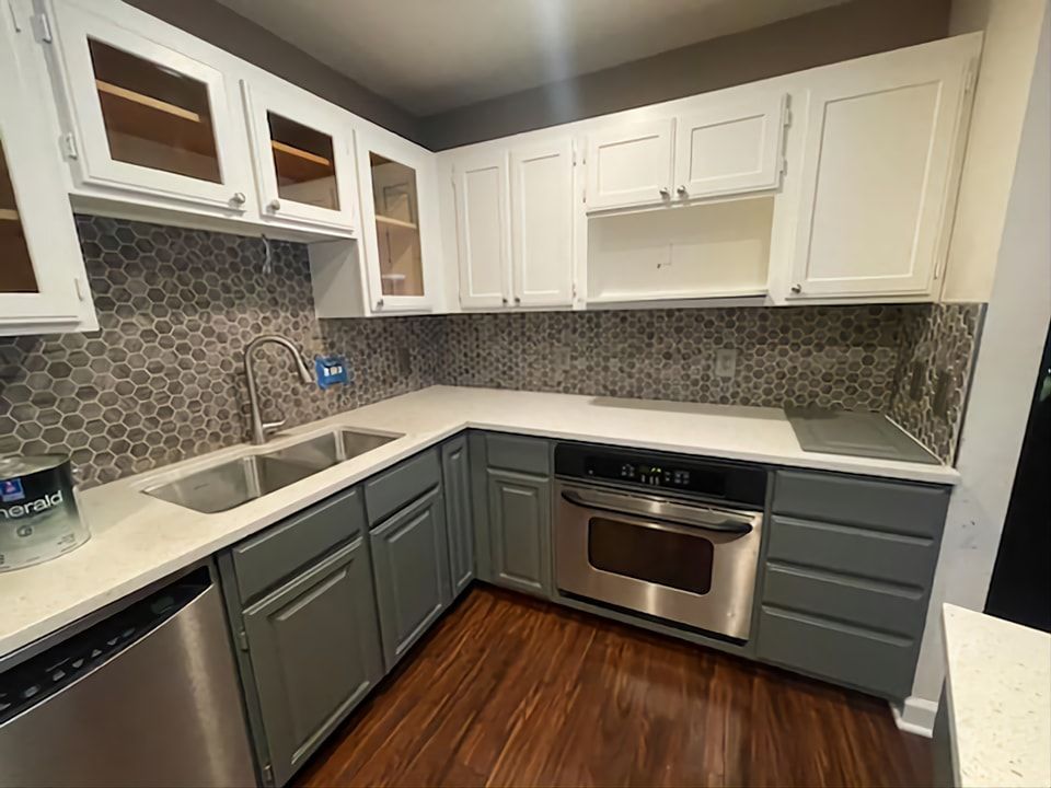 Kitchen with gray and white cabinets, stainless steel appliances, and mosaic backsplash.