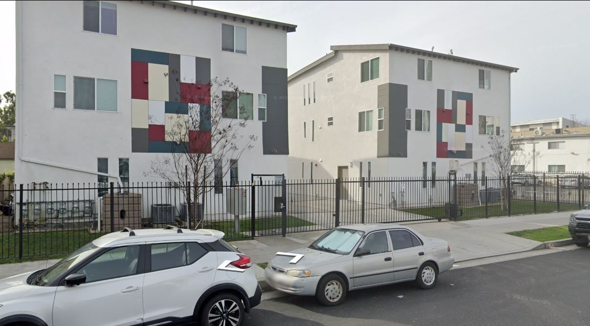 A couple of cars are parked in front of a building.