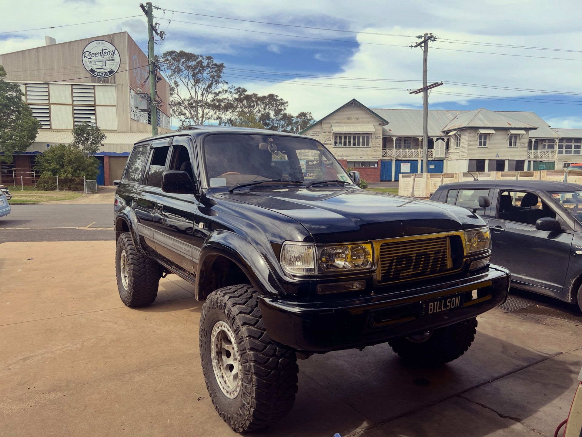 Black lifted SUV with large tires, parked in front of buildings on a sunny day — Bundaberg Radiator Service in Bundaberg East, QLD