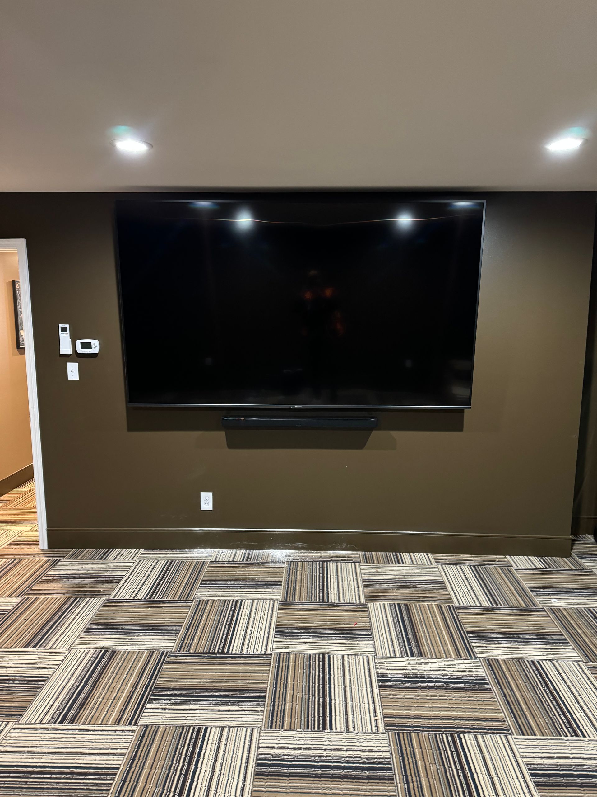 A large flat screen tv is mounted on a wall in a basement.