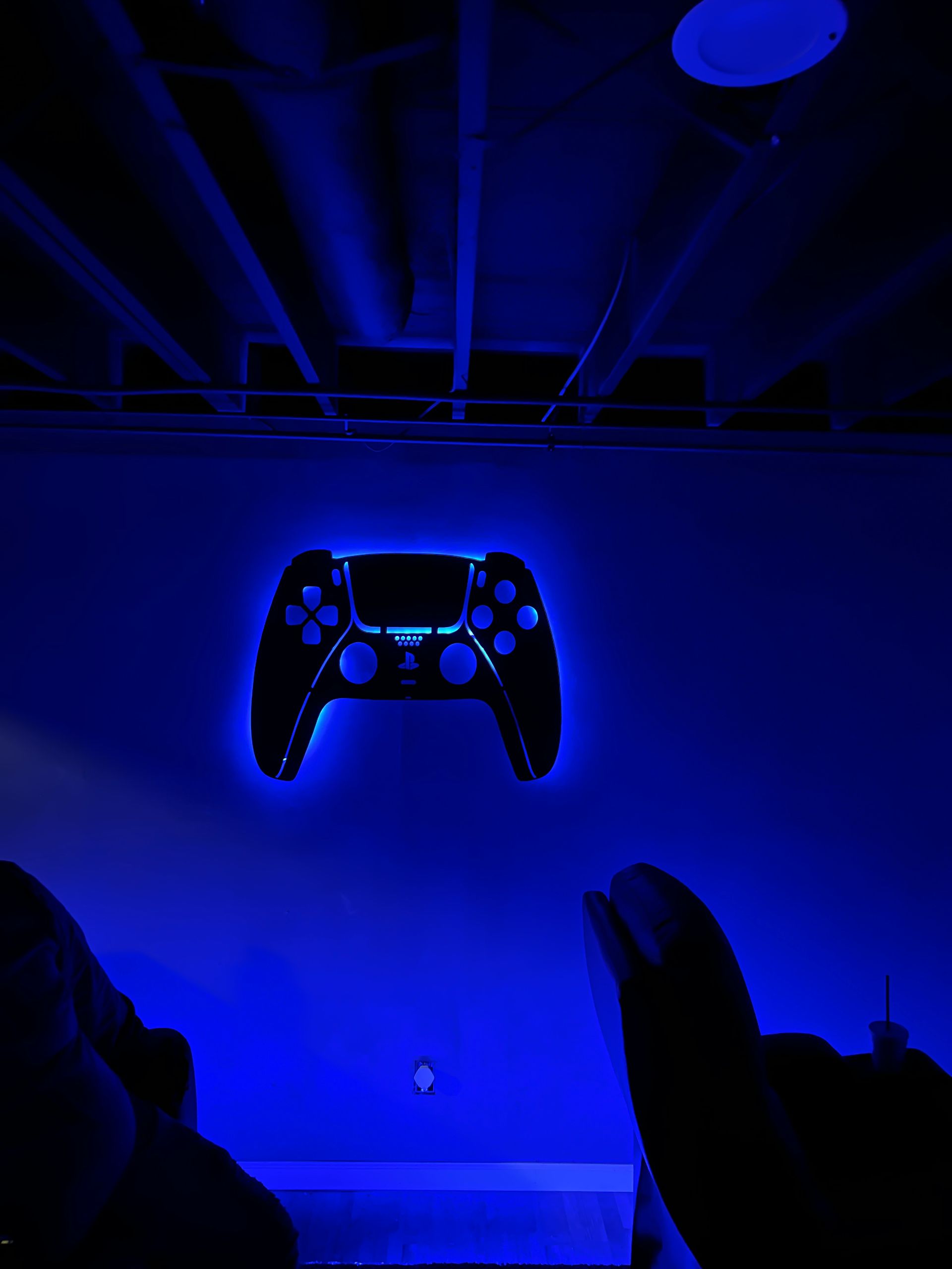 A person is holding a playstation controller in a dark room.
