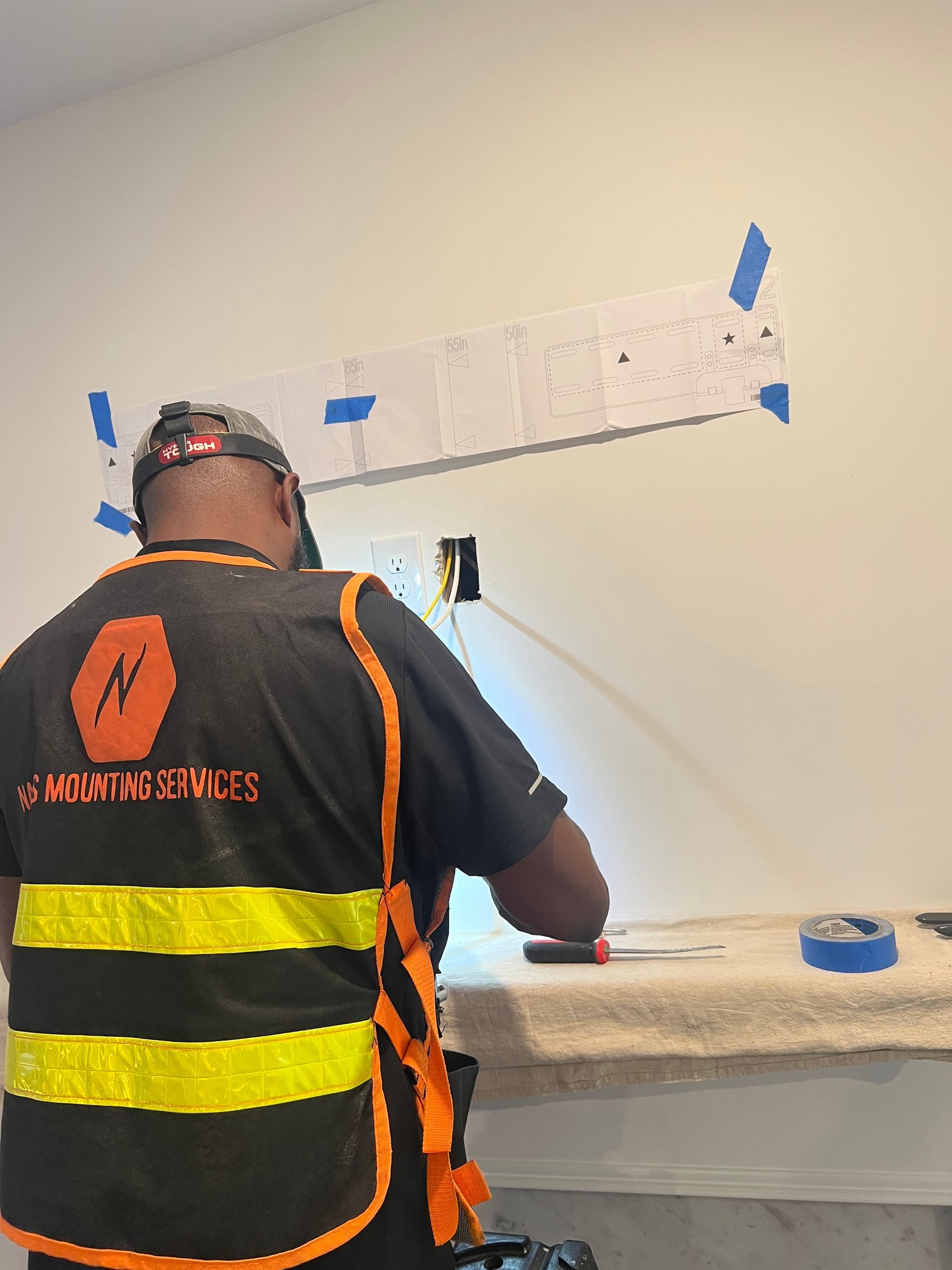 A man wearing a safety vest is working on a wall.