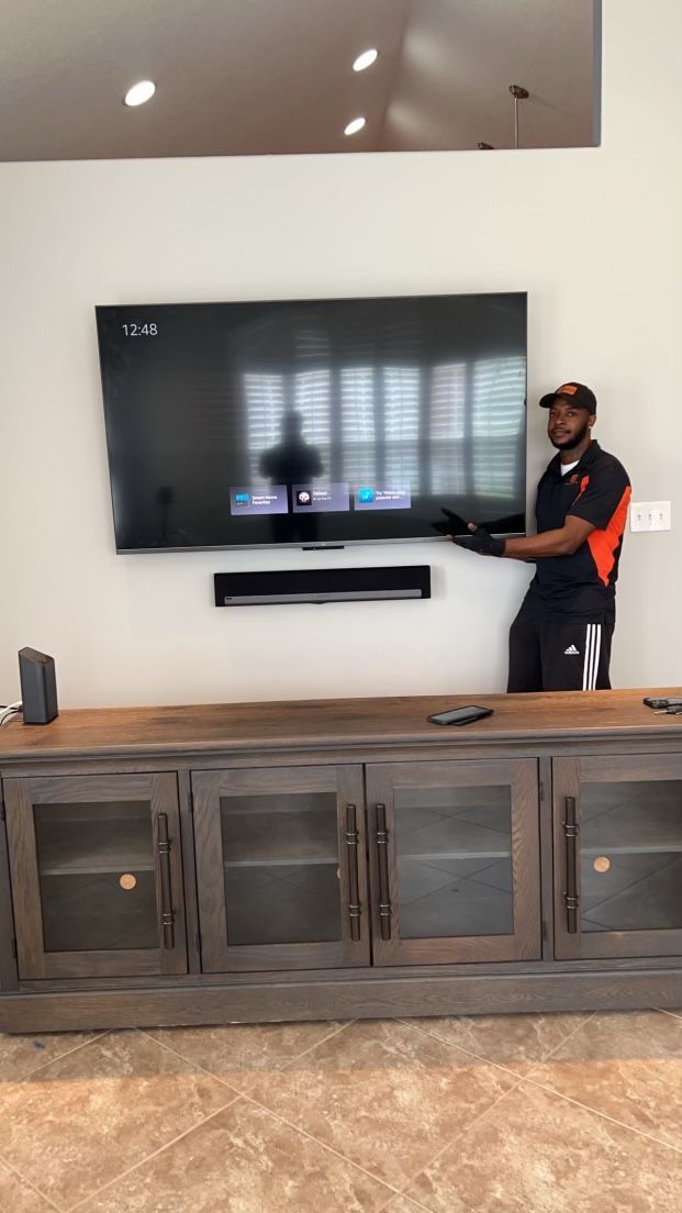 A man is installing a flat screen tv on a wall.