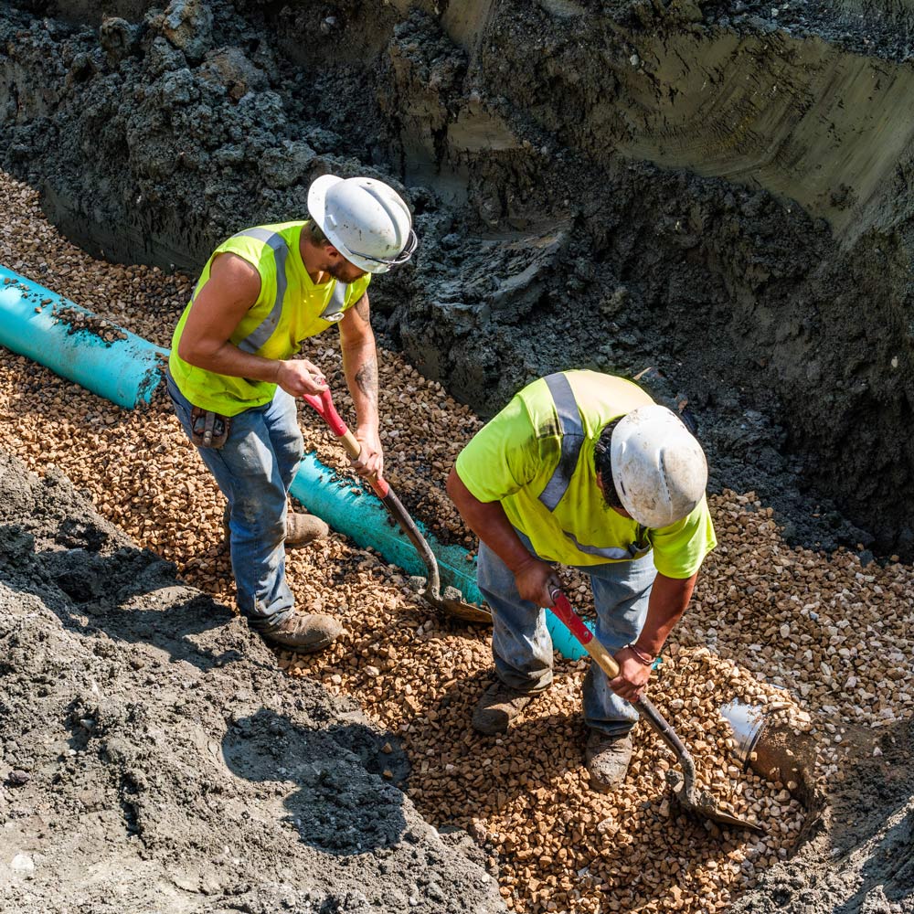 Two Men Working Pipes Underground — Chaska, MN — Kusske Construction Company