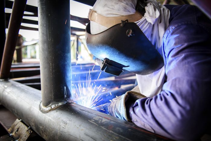 A custom driveway gate is being fabricated by a welder at Sylvan Lake Welding