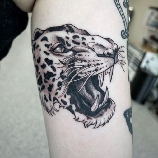 A person has a tattoo of a leopard on their arm