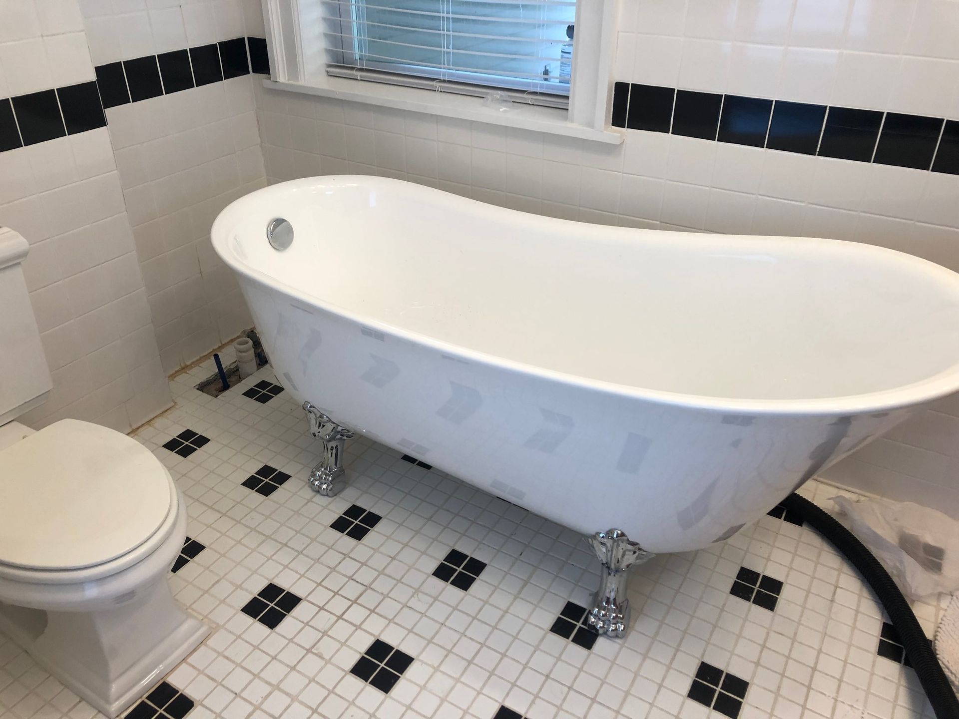 White clawfoot bathtub in a tiled bathroom with black accents.