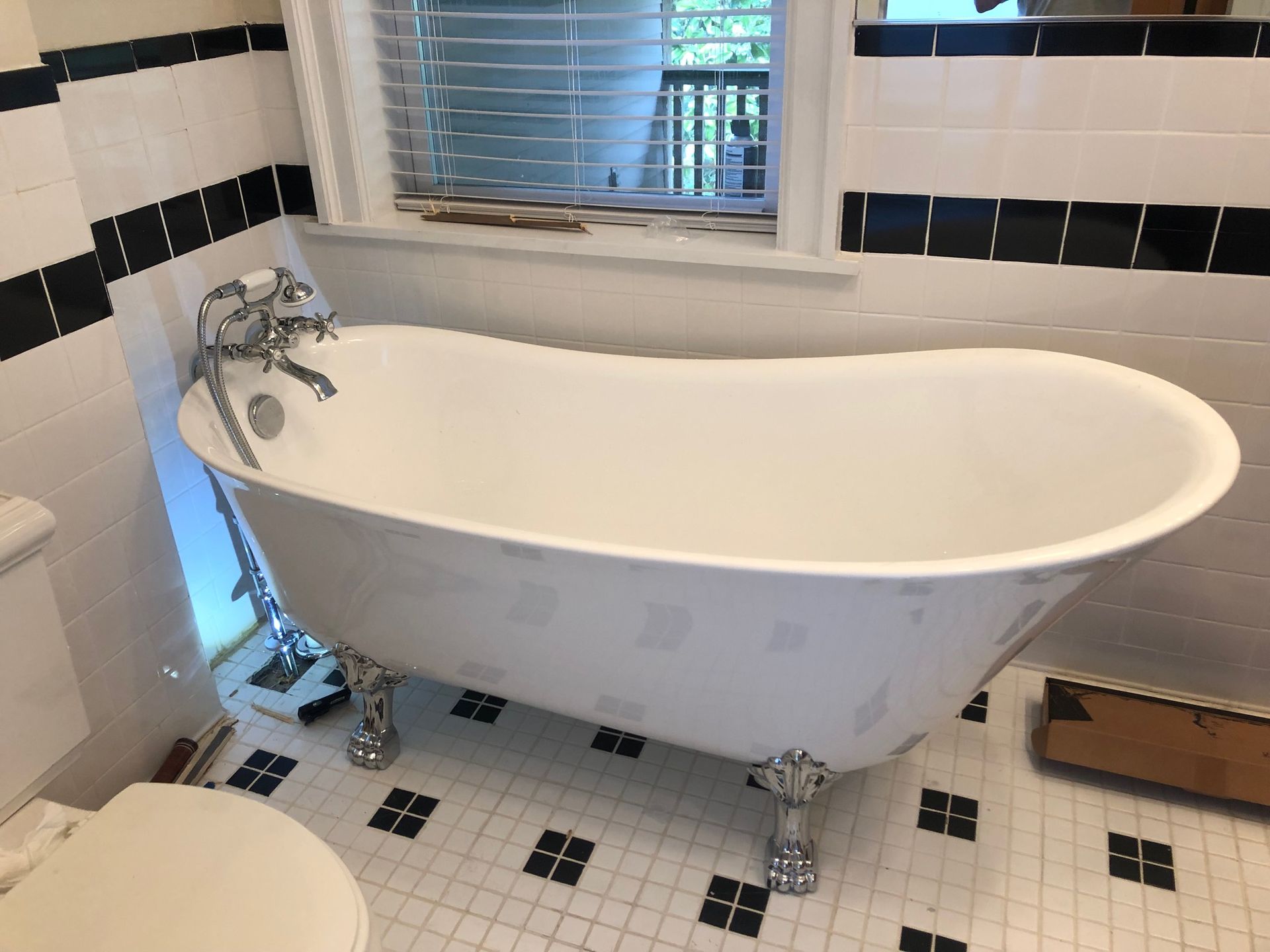 Claw-foot bathtub in a bathroom with black and white tile.