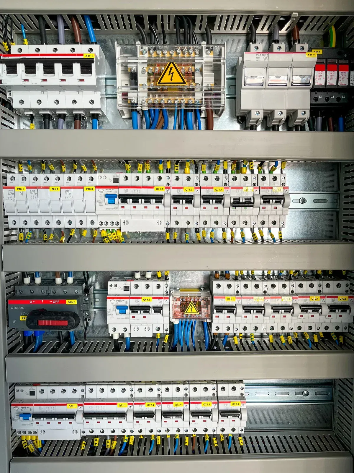 Electrical panel with various circuit breakers, wiring, and safety labels.